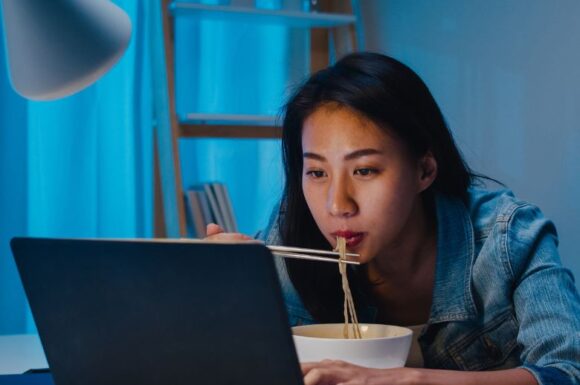 Donna asiatica davanti al pc mentre studia, simbolo di formazione universitaria accessibile.