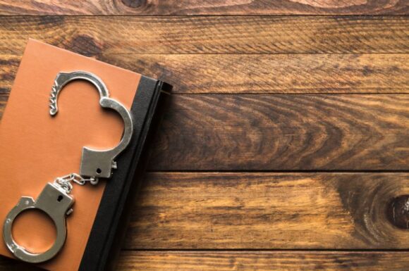 Libro e manette, simboli che richiamano l'idea degli studi penitenziari.